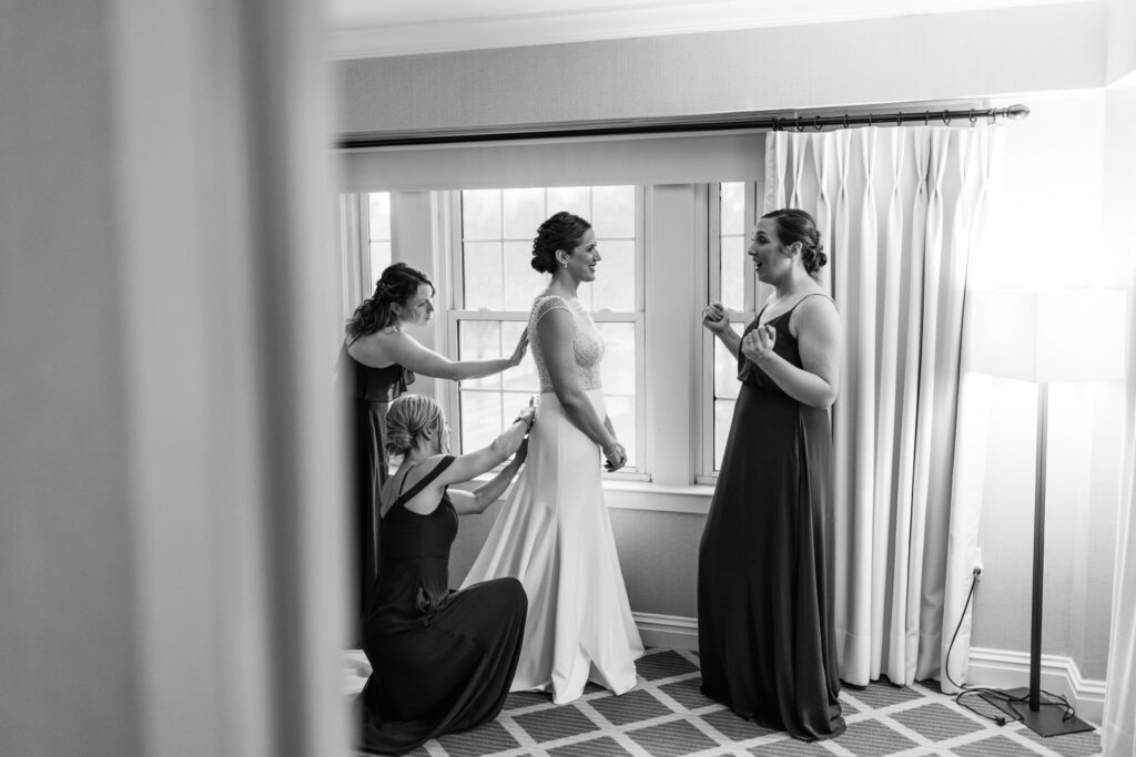 Bridesmaids helping Nicole into her wedding dress