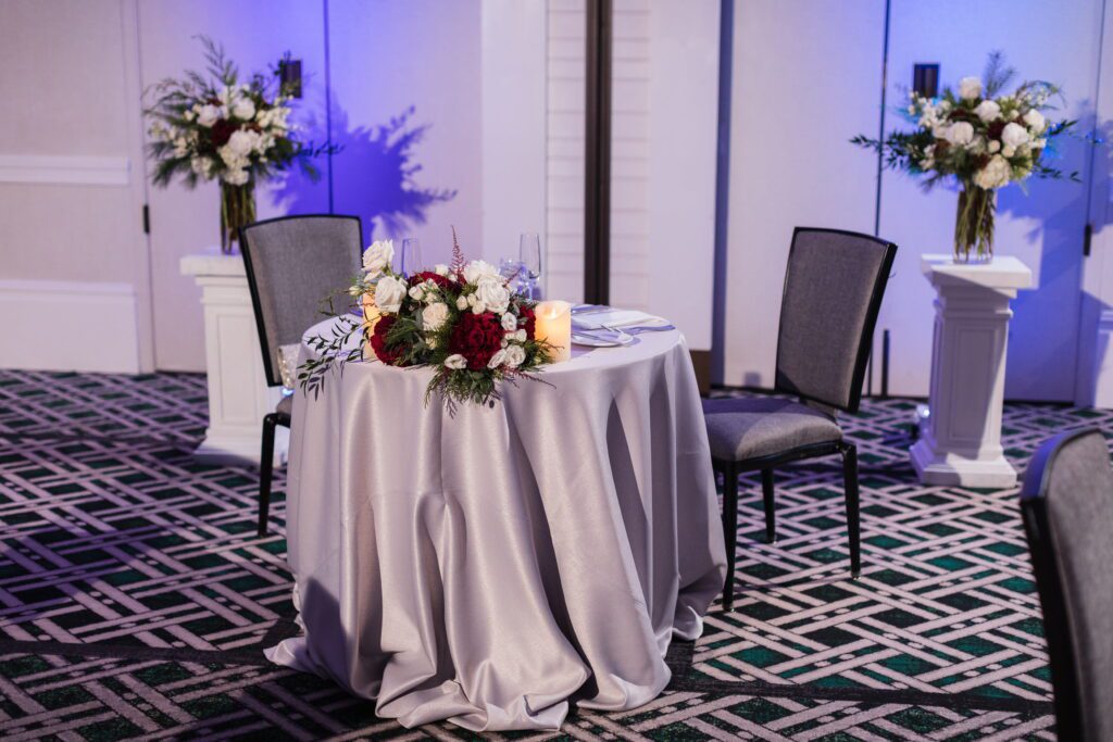 Sweetheart table with burgundy flowers and blue uplighting at Hanover Inn