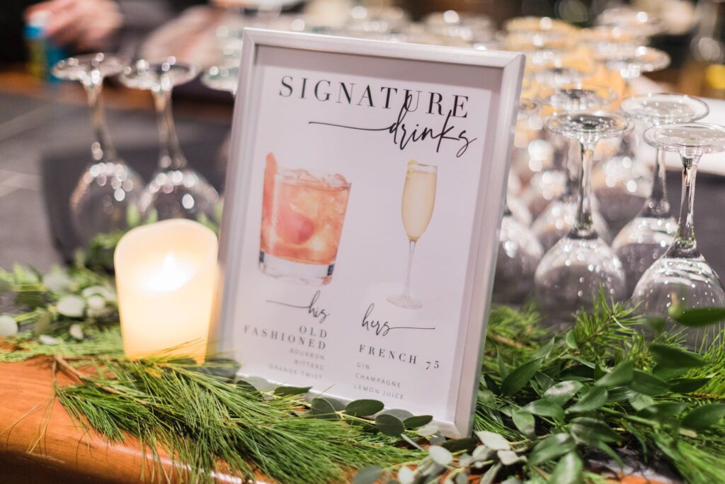 Signature drink sign surrounded by winter greenery and candlelight