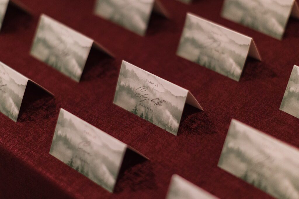 Winter-themed wedding place cards displayed on burgundy linen