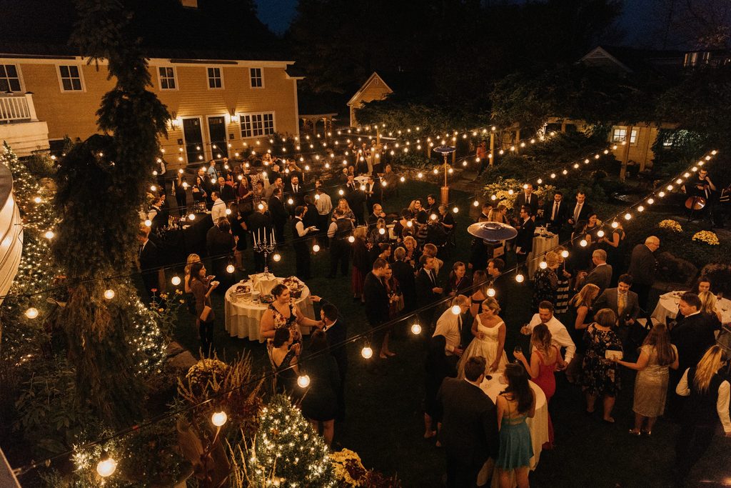 Evening wedding cocktail hour beneath string lights at Bedford Village Inn