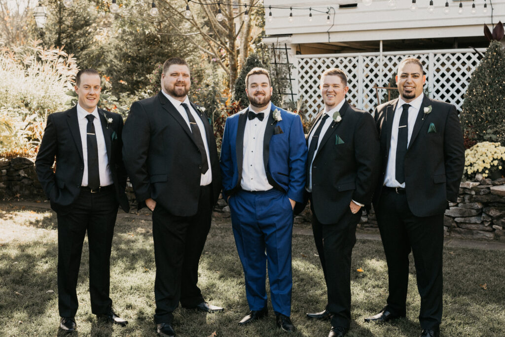 Groom in a blue tuxedo with groomsmen in black suits at Bedford Village Inn in Bedford, New Hampshire