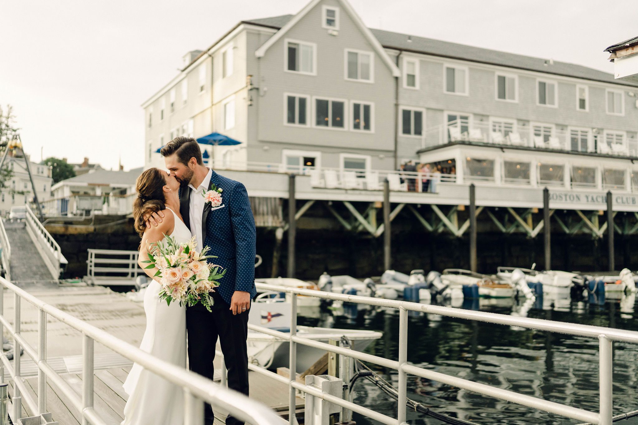 Erin and Rob kissing beside the Boston Yacht Club in Marblehead