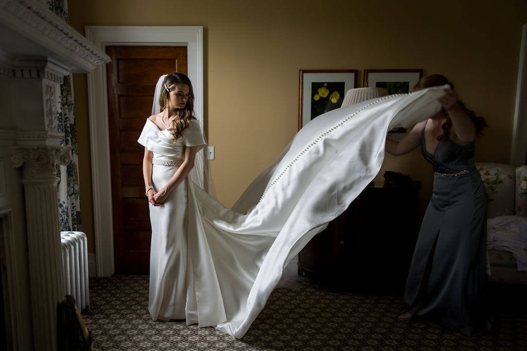 Bridesmaid arranging Katie’s long wedding dress train before the ceremony