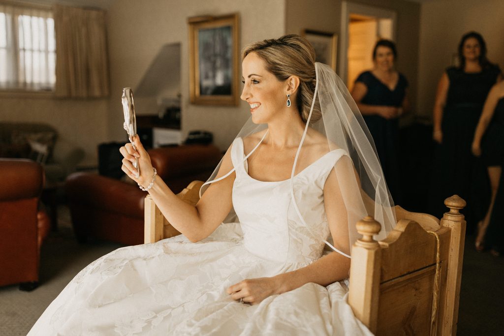 Portrait of Kerry looking into a mirror before the ceremony