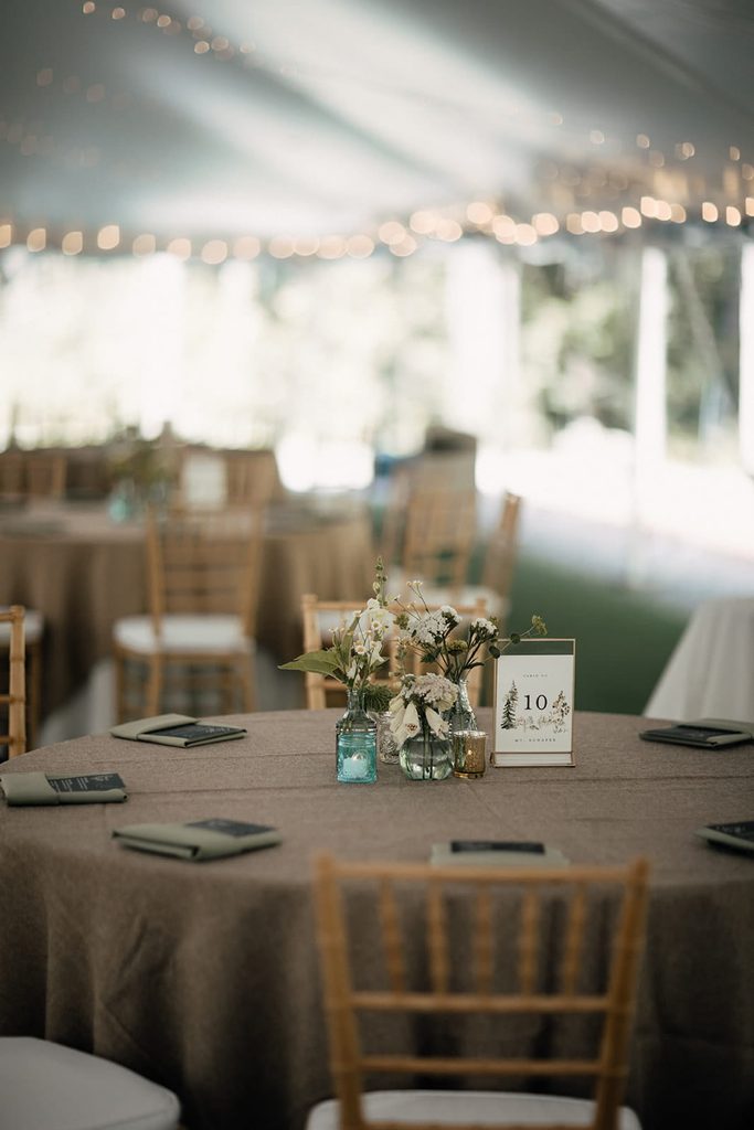 Burlap wedding table with minimal flowers inside the Dexter’s Inn reception tent