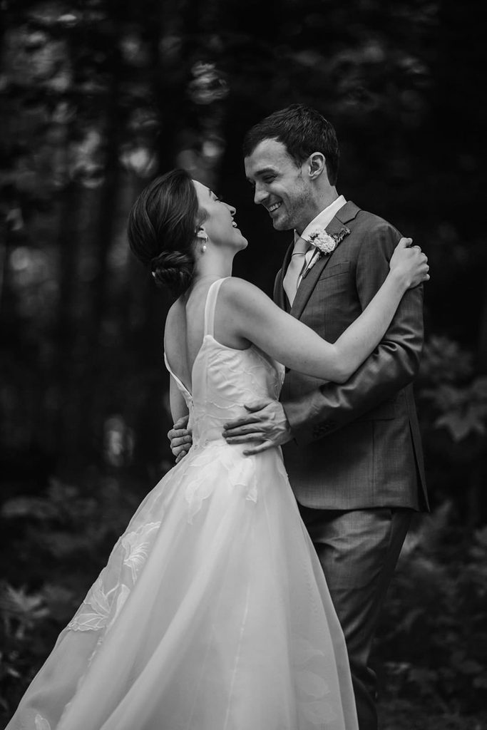 Black-and-white portrait of Caroline and Arthur smiling in the woods
