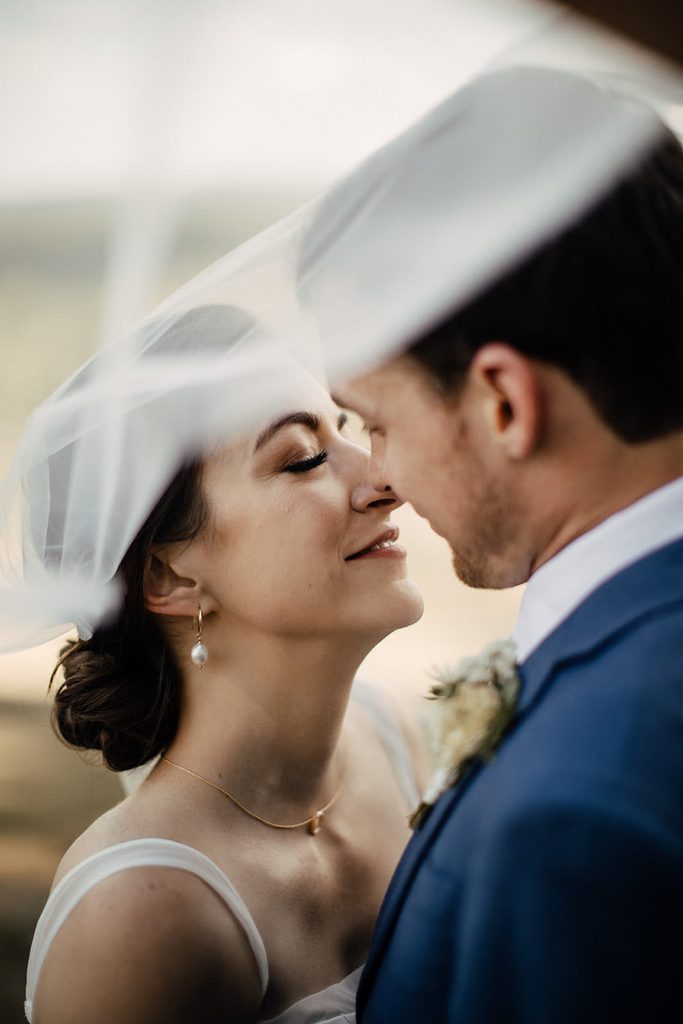 Close portrait of Caroline and Arthur beneath her wedding veil