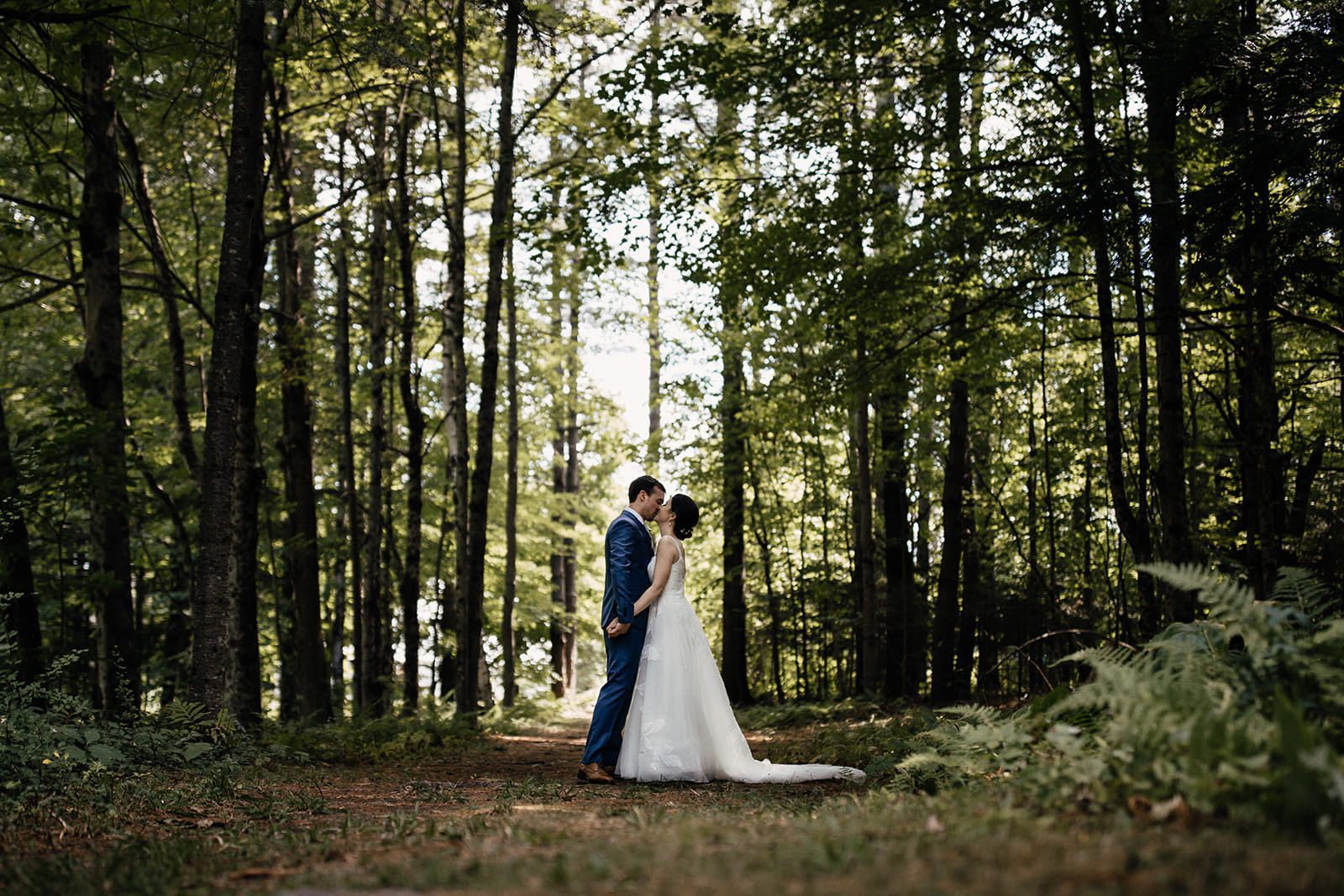 Caroline and Arthur kissing on a wooded trail at Dexter’s Inn