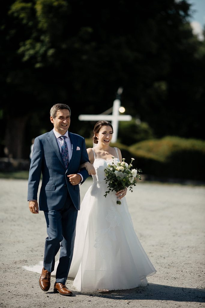 Caroline walking to her outdoor wedding ceremony with her father