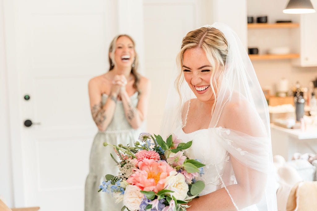 Emily laughing while holding her colorful wildflower bridal bouquet