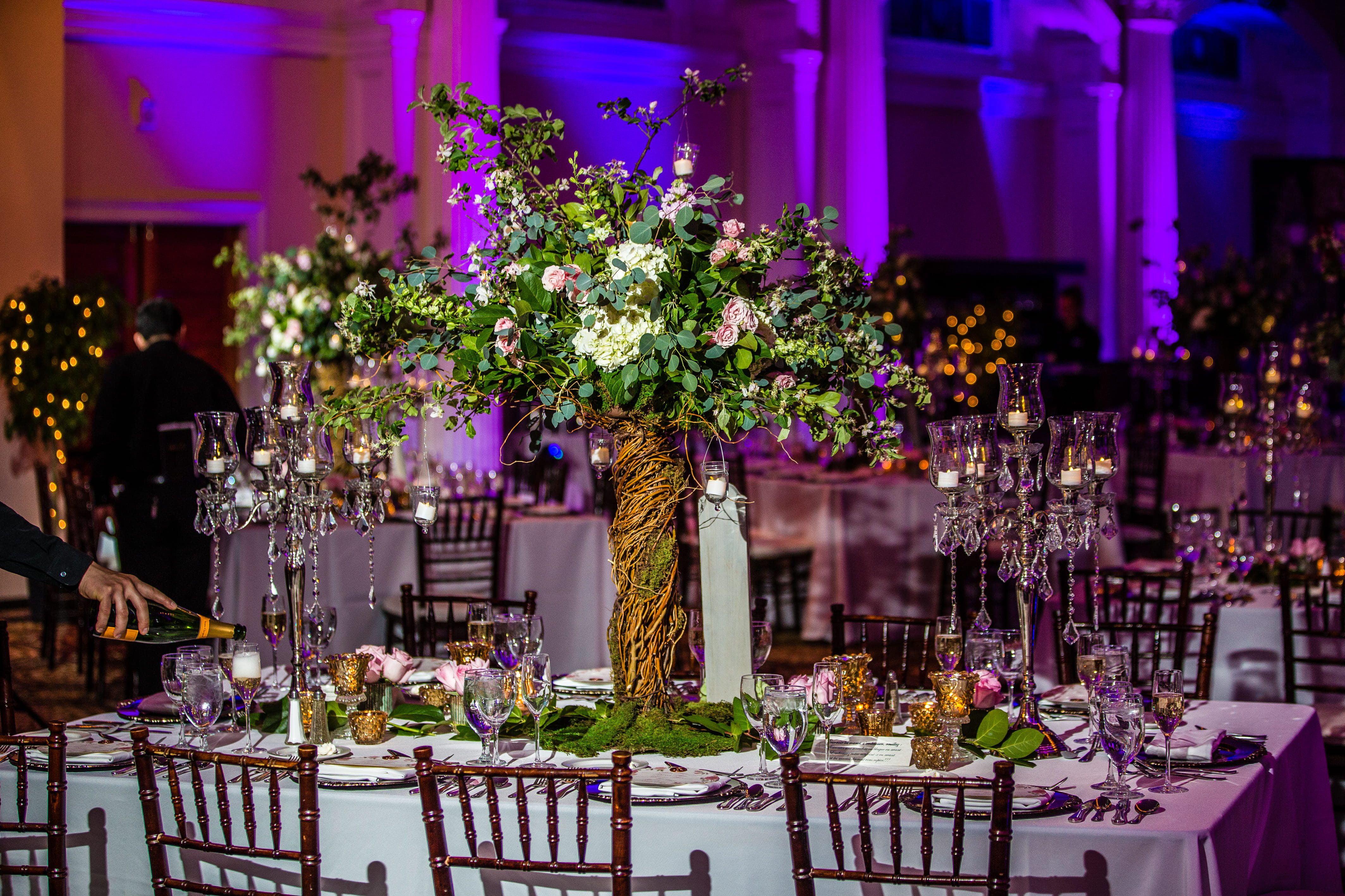 Tall enchanted forest centerpiece with greenery, pink flowers and candles