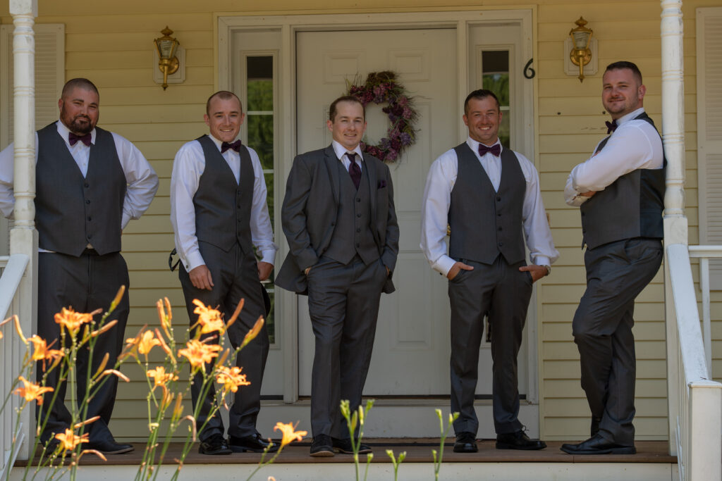 Groomsmen wearing gray vests and burgundy bow ties for an outdoor New England wedding