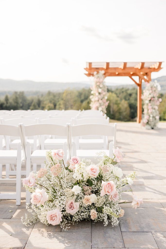 Grounded pink and white floral arrangement beside the ceremony aisle at Owl’s Nest Resort in Thornton, New Hampshire