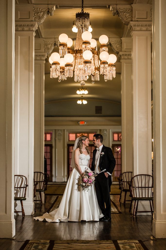 Francesca and Bernard beneath a chandelier inside the historic Omni Mount Washington Resort