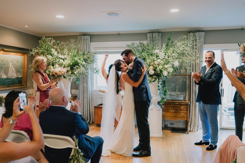Erin and Rob kissing during their indoor Boston Yacht Club wedding ceremony