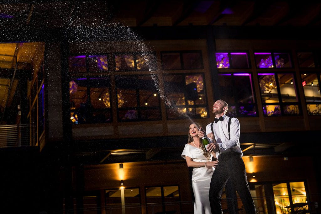 Katie and Alex popping champagne outside Rosebrook Lodge at night