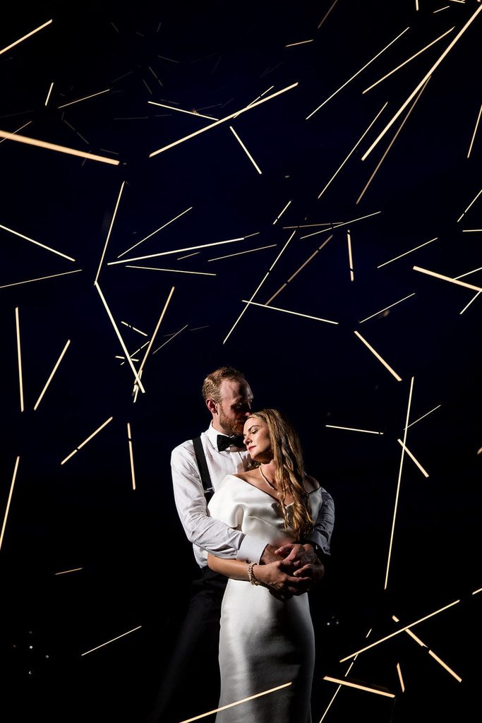 Katie and Alex embracing beneath glowing sparks at Rosebrook Lodge