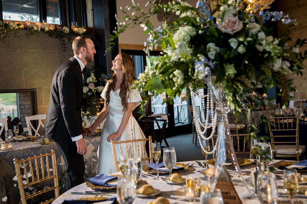 Katie and Alex laughing together among the reception tables at Rosebrook Lodge