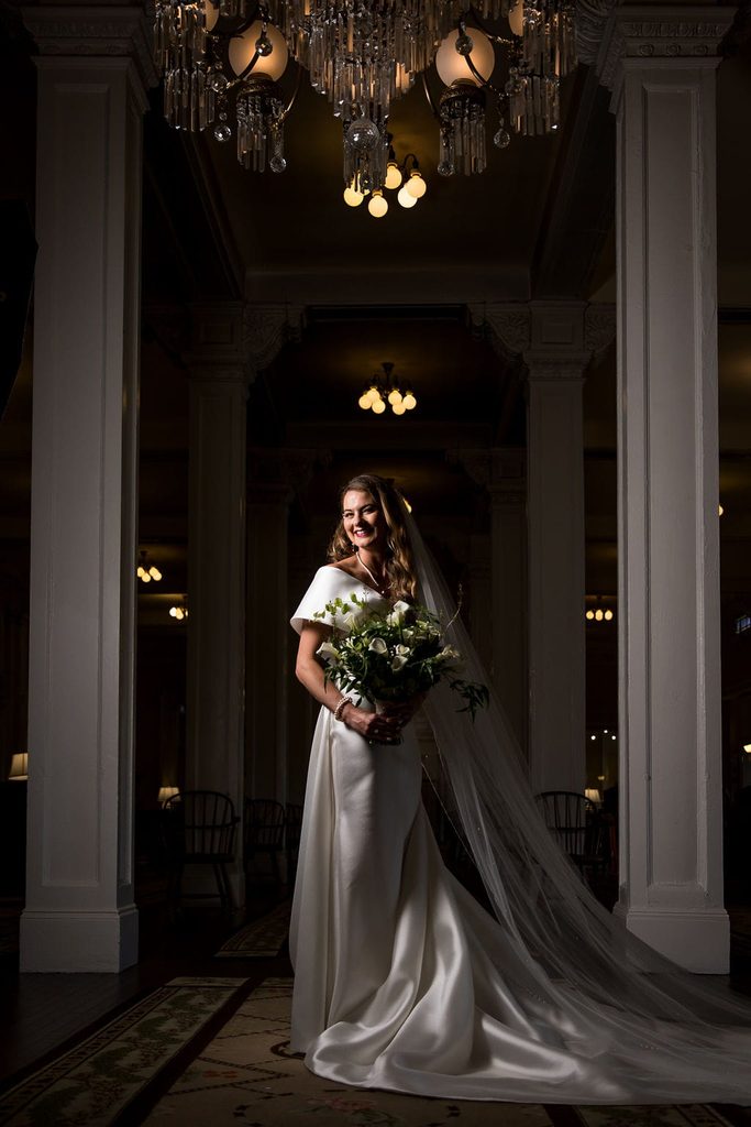 Katie holding her bouquet beneath the chandeliers at the Omni Mount Washington