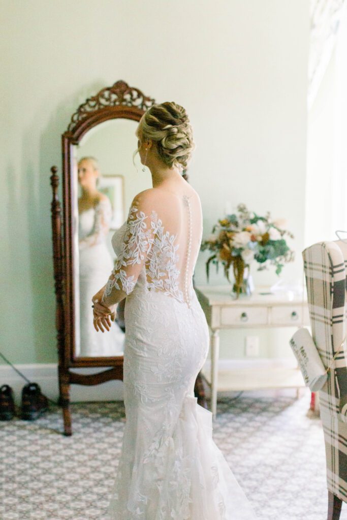 Nicole admiring her lace wedding gown in the mirror before the ceremony