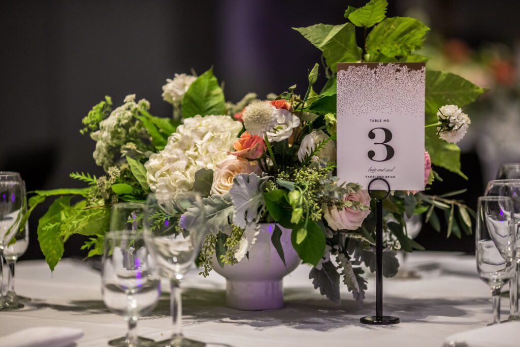 Peach and white wedding centerpiece with table number three