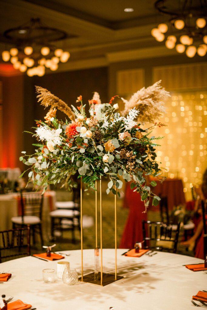 Tall fall wedding centerpiece with orange flowers, eucalyptus and pampas grass
