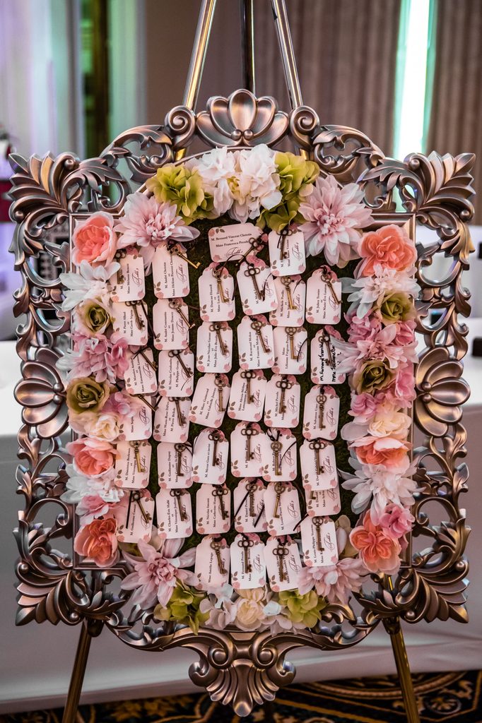 Vintage key escort cards displayed with pink flowers and moss