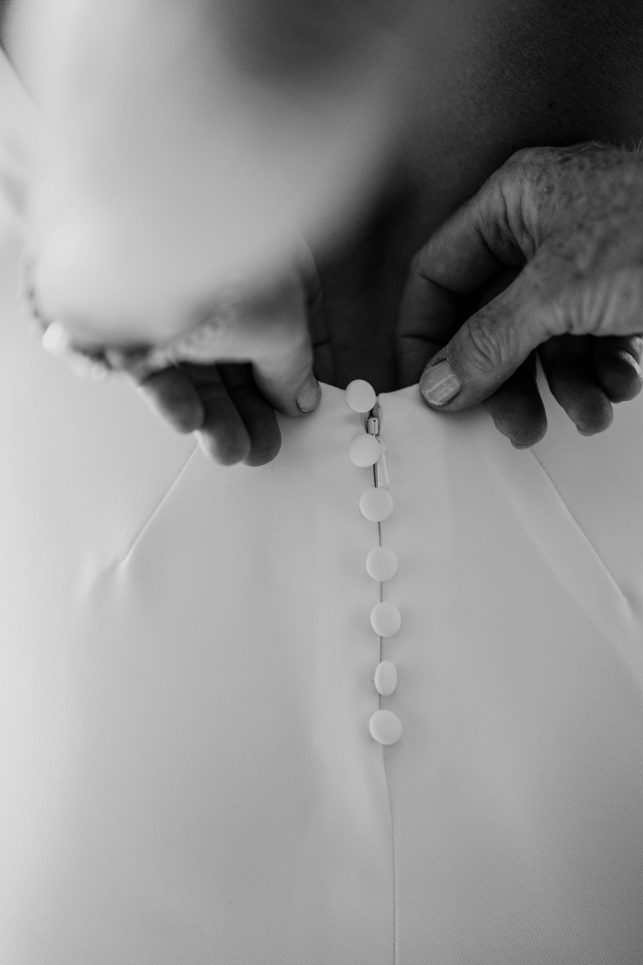 Close-up of the buttons being fastened on Erin’s wedding dress