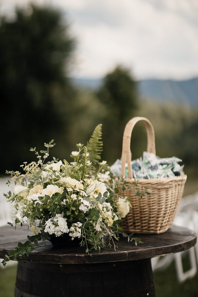 White and green ceremony flowers displayed on a wooden barrel