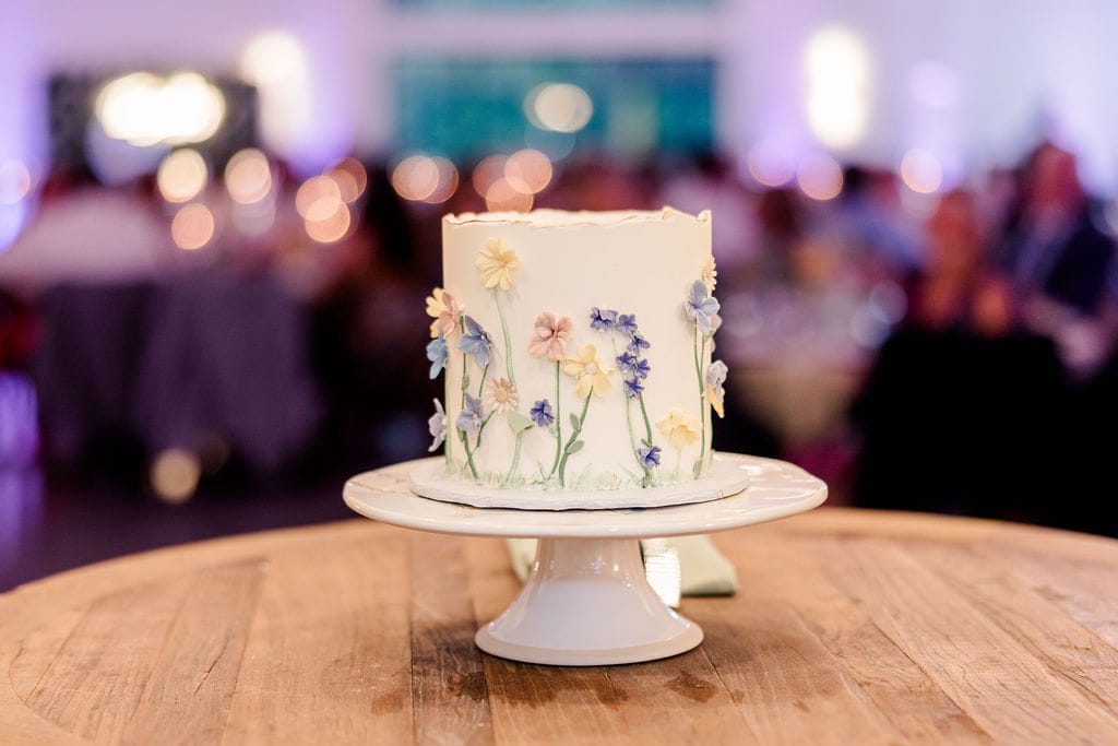 White wedding cake decorated with delicate pastel wildflowers