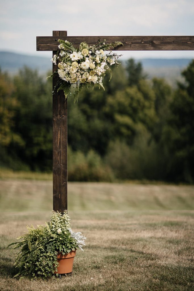 Wooden ceremony arbor decorated with white flowers and ferns overlooking the mountains